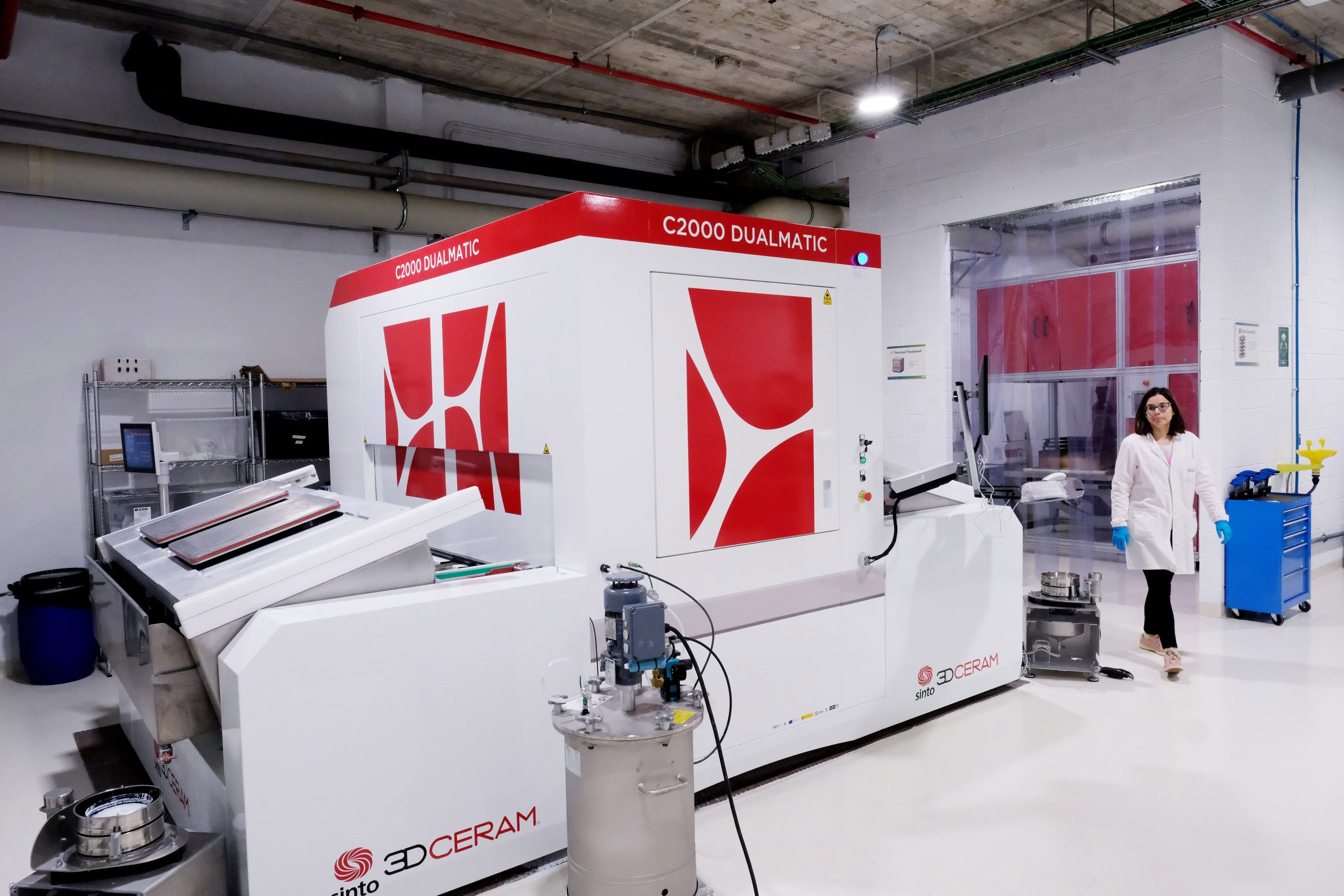 Scientist working in an energy research laboratory next to a large-scale experimental machine for advanced materials testing and autonomous laboratory processes.
