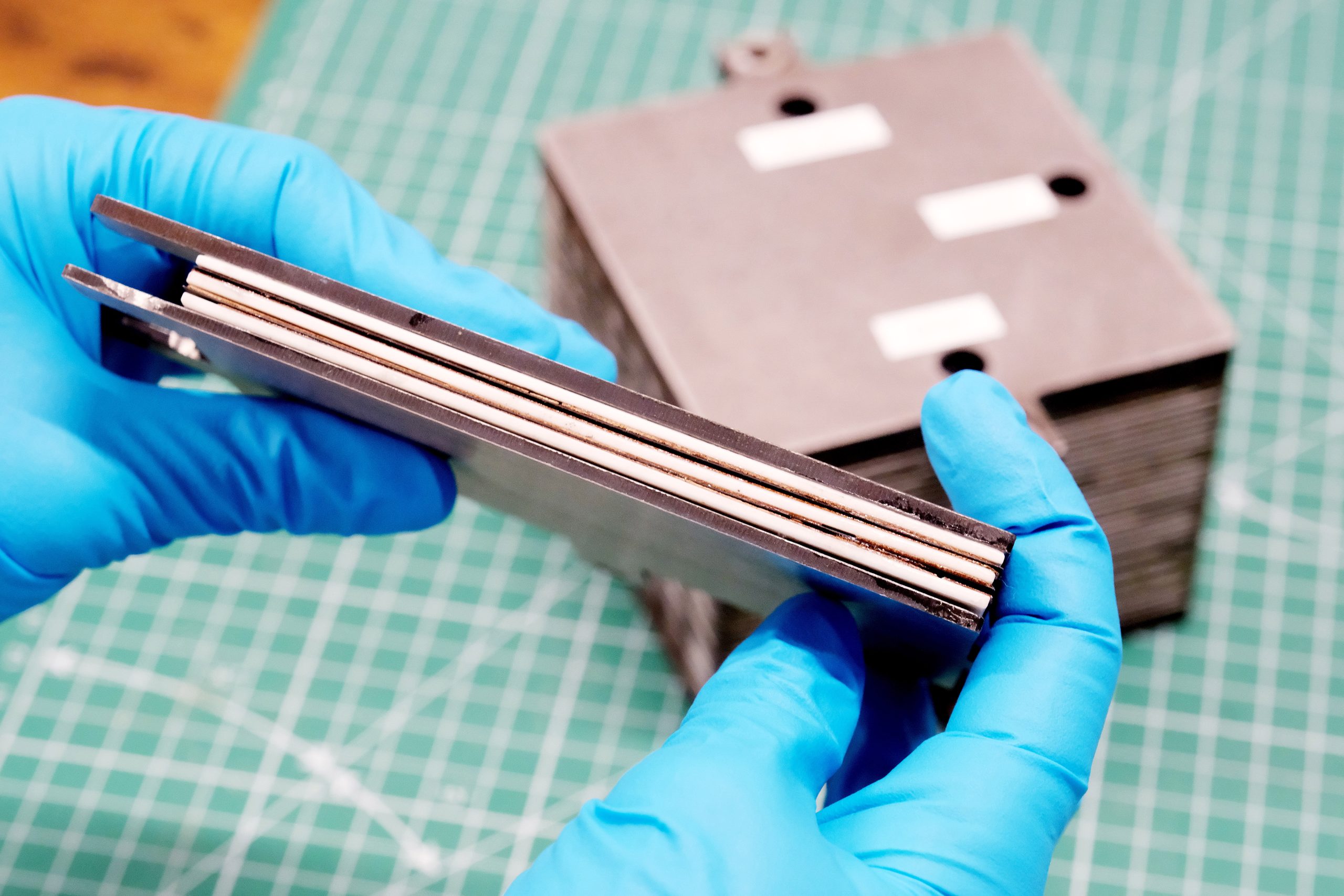 Scientist demonstrating a section of a solid oxide fuel cell, highlighting advanced materials and layered structure for hydrogen production and renewable energy applications.