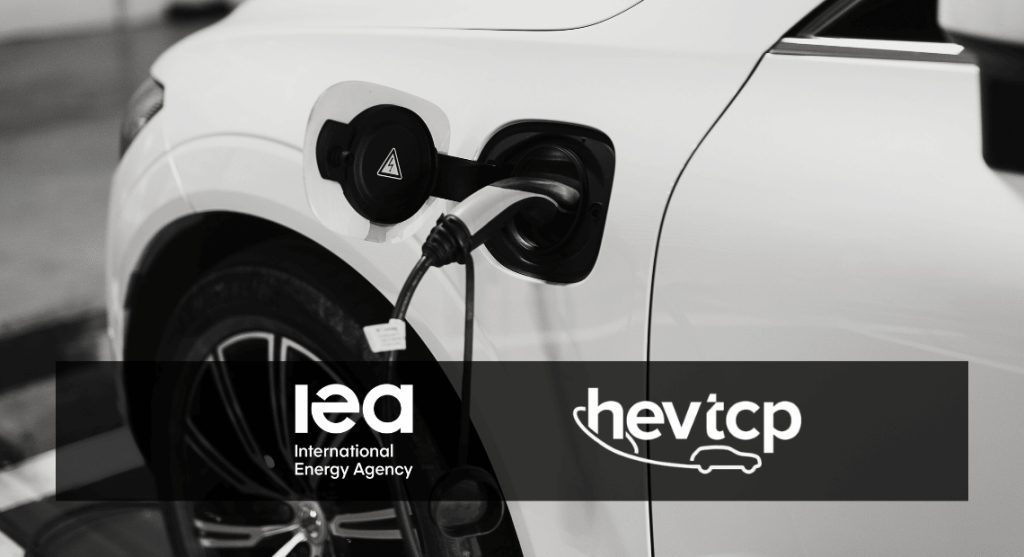 Close-up of a white electric vehicle being charged, with the IEA and HEV-TCP logos overlaid at the bottom.