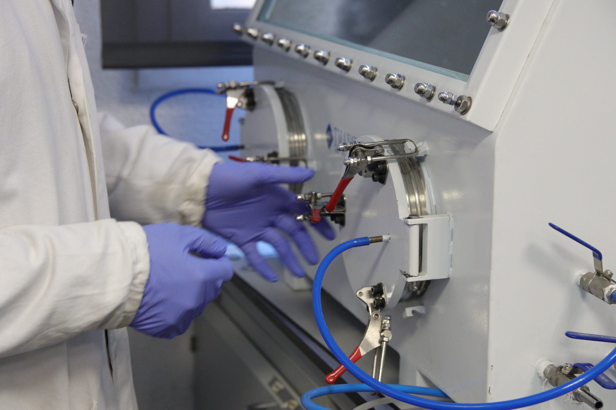 Scientist adjusting advanced laboratory equipment for automated materials testing and AI-driven experimentation in energy research.