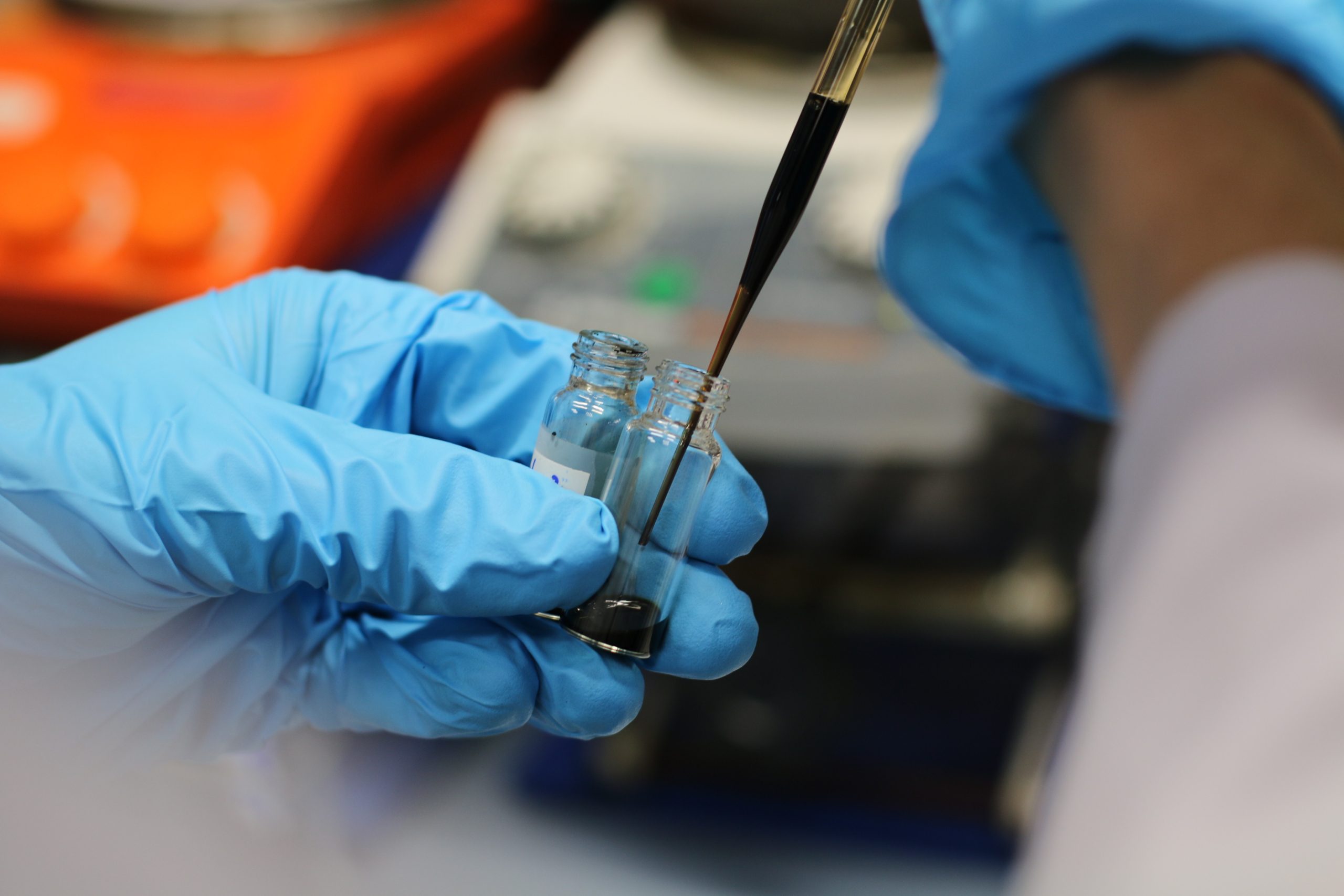 Scientist pouring liquid into a laboratory container, representing nanoparticle ink processing and advanced fabrication of functional materials for thin films, nanocomposites and microdevice manufacturing.