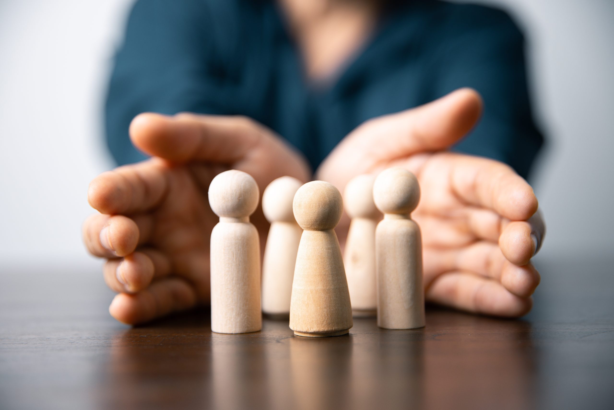 Hands cupped around small wooden figures, illustrating IREC’s focus on human-centric innovation and the protection and safety of its workforce.