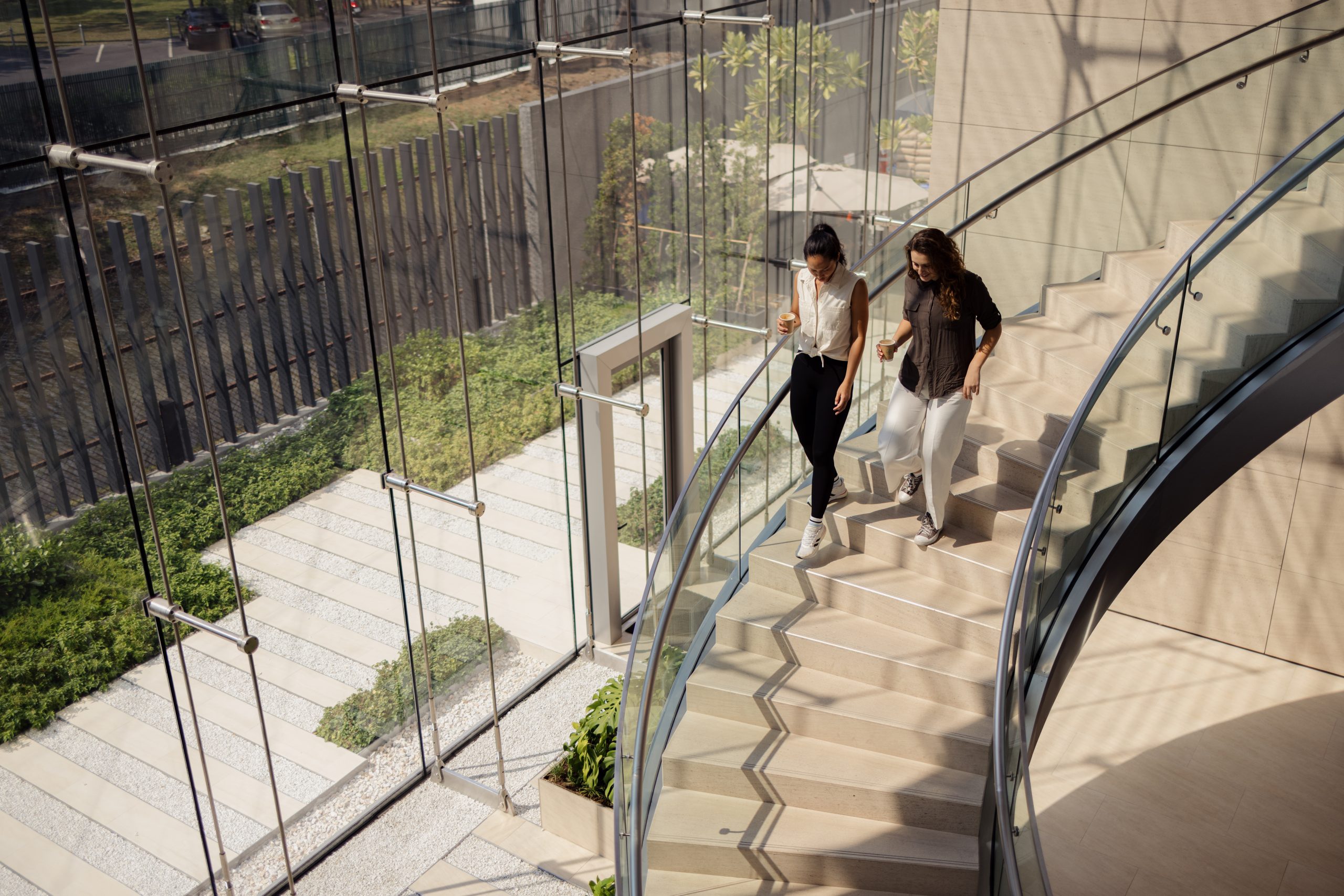 Two colleagues walking down a modern staircase, representing the fluid collaboration and synergy essential for successful project management at IREC.