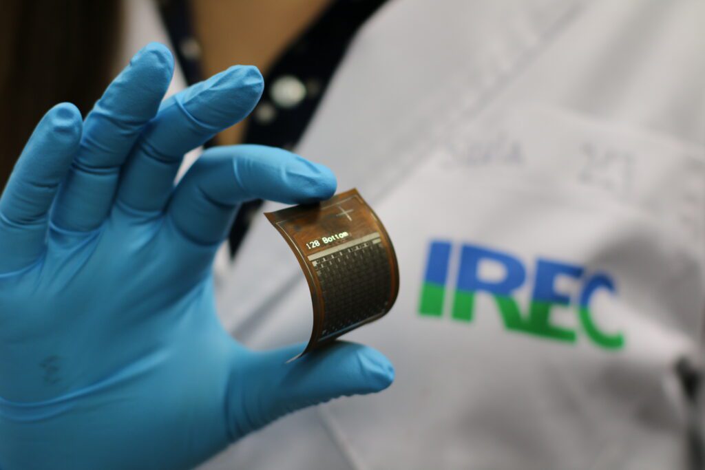Investigador de IREC sosteniendo un dispositivo energético flexible en un laboratorio, representando la investigación avanzada en tecnologÃas de energÃas renovables, la innovación y soluciones sostenibles para abordar los retos energéticos globales y mejorar la competitividad industrial.