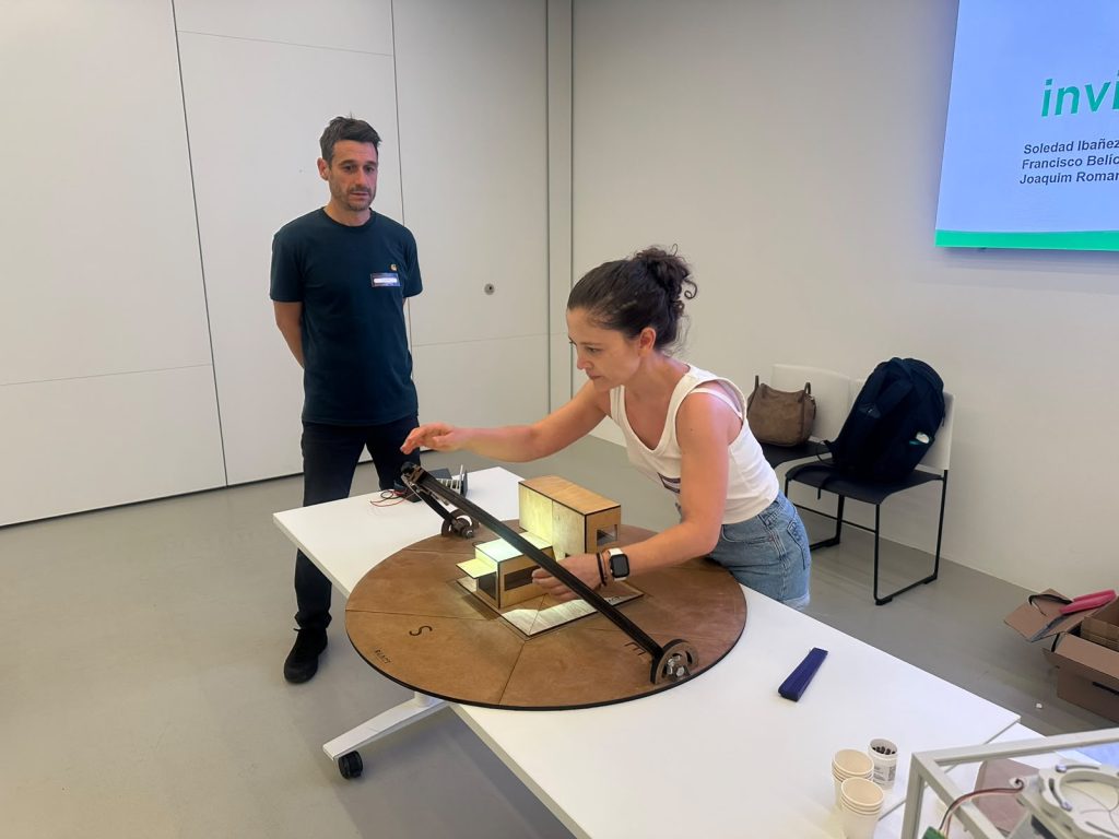 Participants exploring solar energy and ventilation concepts through a hands-on housing model during IREC’s “Invisible Energy at Home” workshop.