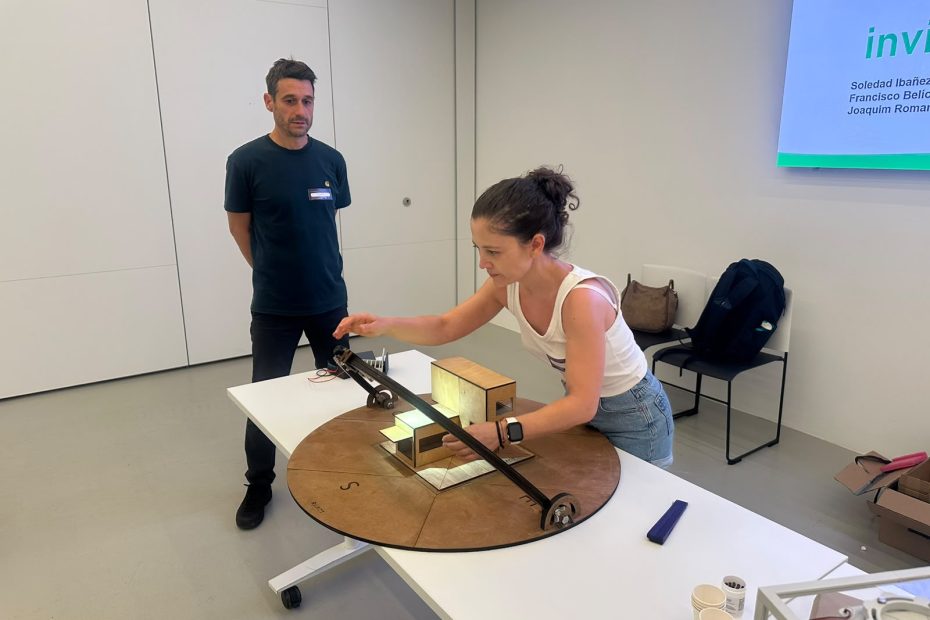 Participants exploring solar energy and ventilation concepts through a hands-on housing model during IREC’s “Invisible Energy at Home” workshop.